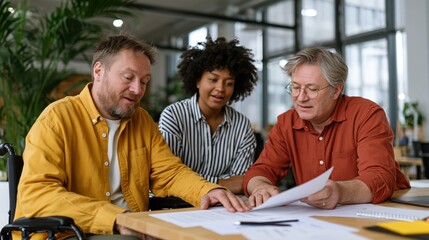 Fototapeta premium Diverse team collaborates on documents, including a wheelchair user in a meeting