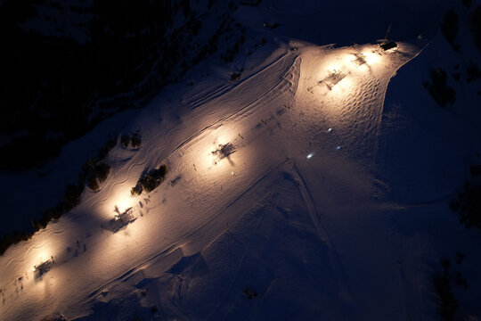 Aerial view of Les Crosets ski resort at night with illuminated slopes and chairlift stations in Val-d'Illiez, Valais, Switzerland.