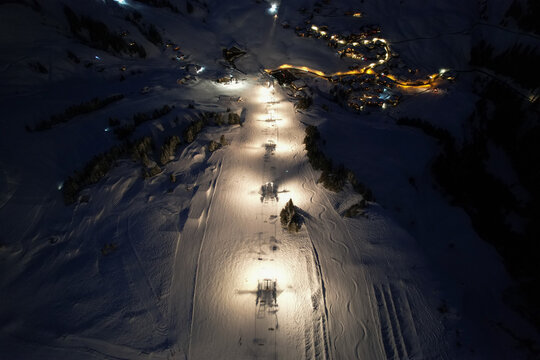 Aerial view of Les Crosets ski resort at night with illuminated slopes and chairlift towers in the snowy mountains of Val-d'Illiez, Valais, Switzerland.