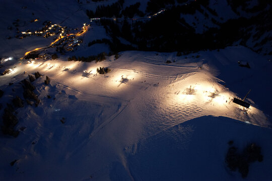 Aerial view of Les Crosets ski resort at night with illuminated slopes, ski lifts, and snow-covered mountain peaks in Val-d'Illiez, Valais, Switzerland.