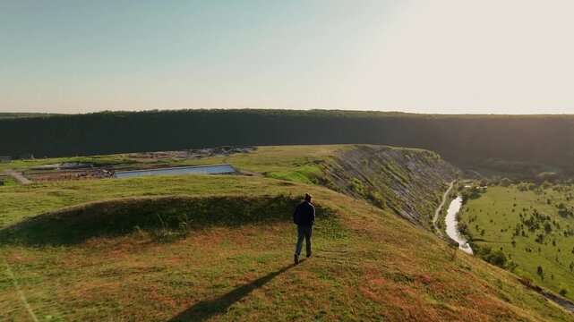 Person Hiking On Grassy Ridge Overlooking River, Golden Light, Long Shadow, Panoramic Valley, Calm Water