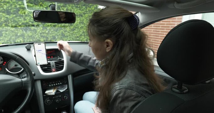 Woman mounts smartphone for car navigation on a clear day