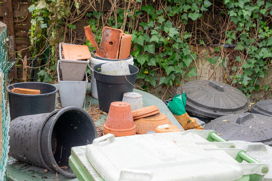 Empty Plastic Flower Pots and Garden Containers Stacked Outdoors,Stack of Old Plastic Gardening Pots for Reuse or Recycling,Messy Garden Storage Area with Pots and Bins,