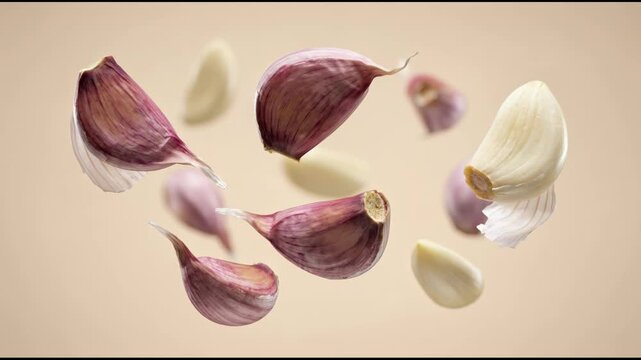 Slow motion footage of fresh garlic cloves levitating against a neutral background featuring cinematic lighting and professional food styling for organic cooking and health concepts.