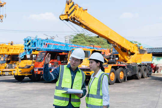 Engineers discuss crane inspection and safety planning in a heavy equipment yard, reviewing lifting operations, maintenance risks, and industrial worksite readiness.