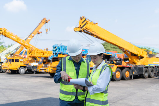 Engineers review a crane inspection checklist with radio communication in a heavy equipment yard, supporting safety control, maintenance planning, and lifting readiness.