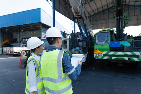 Engineers conduct crane inspection in a maintenance shed, reviewing equipment condition and safety procedures to support lifting readiness, service planning, and compliance.