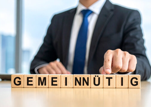 gemeinnützig - Geschäftsmann zeigt auf den Text "gemeinnützig"