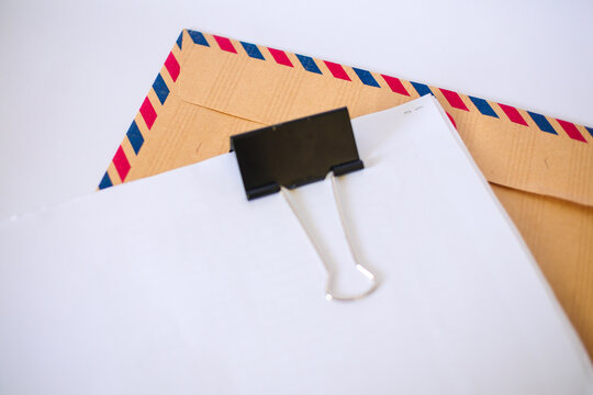 Blank paper with binder clip on airmail envelope isolated on white