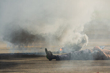 Fototapeta premium Selective smoke from smoke bomb and out of focus terrorist lies dead during military assault drill.The criminal was killed by riot police.A drill simulating a rescue operation against terrorists