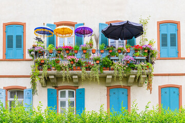 Obraz premium Colorful balcony filled with flowers and umbrellas in a sunny location