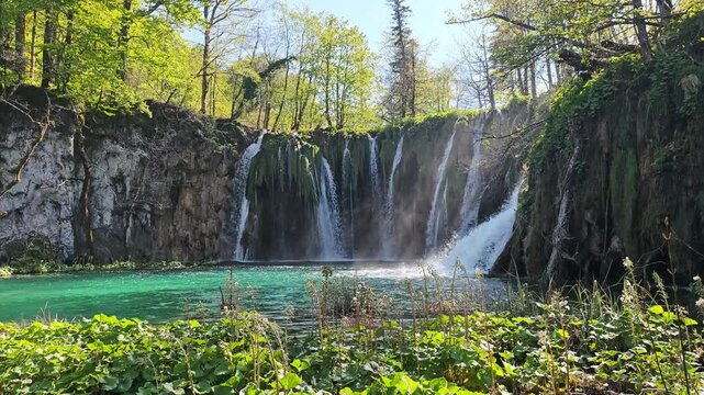 Beautiful waterfalls cascading into a crystal clear turquoise lake with a wooden walkway in Plitvice Lakes National Park, Croatia