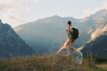 Naklejka premium Woman hiking through an alpine meadow with a backpack in a rugged mountain landscape, embracing outdoors travel lifestyle with a focused, serene mood