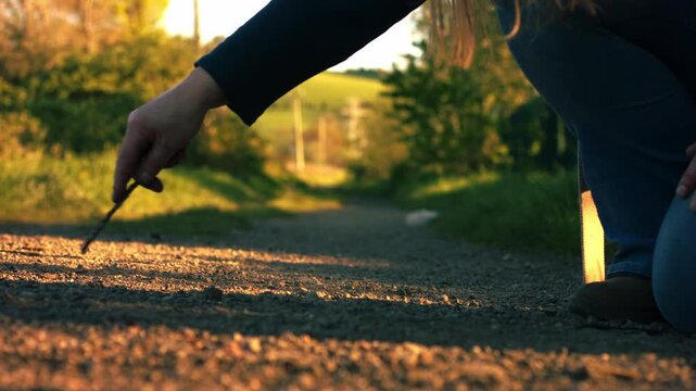 Hand doodling with stick on dusty path
