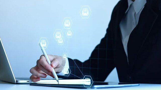 Business person uses digital pen on tablet with virtual icons in modern office space during daytime work session.