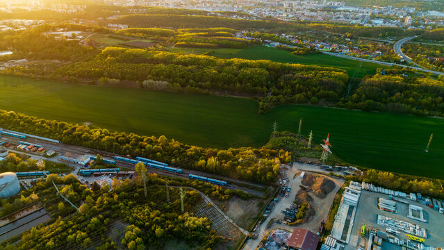 Aerial view of Malesice Infrastructure Objects with trains on tracks, green fields, and industrial buildings during golden hour in Hlavni mesto Praha, Hlavni mesto Praha, Czechia.