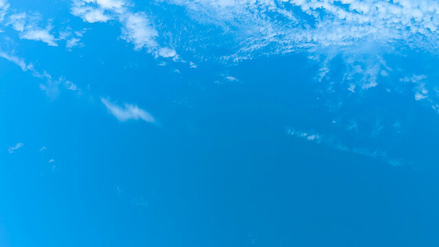 Clear bright blue sky with sparse white clouds panorama.