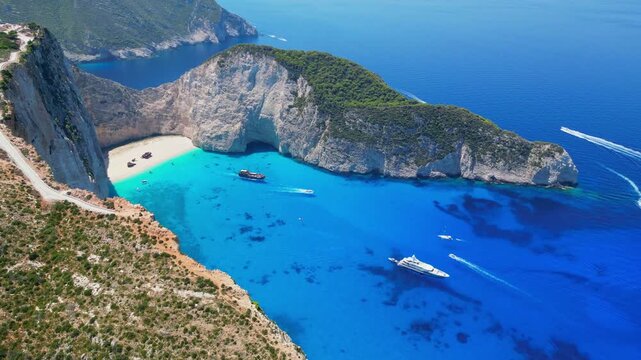 Spectacular view of the iconic Shipwreck beach in Navagio Bay, Zakynthos. Famous rusted boat on white sand surrounded by massive limestone cliffs and turquoise Ionian Sea water.
