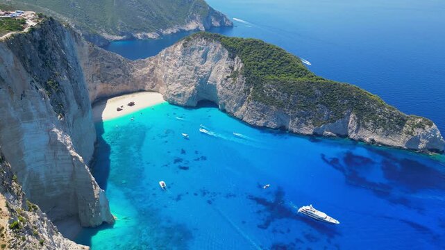 Spectacular view of the iconic Shipwreck beach in Navagio Bay, Zakynthos. Famous rusted boat on white sand surrounded by massive limestone cliffs and turquoise Ionian Sea water.