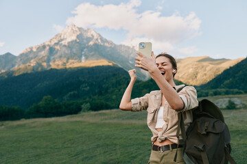 Naklejka premium Selfie taking hiker woman with backpack smiles in the mountains during daytime outdoors
