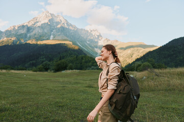 Fototapeta premium Bright woman outdoors hiking backpack nature mountain scenery travel leisure, enjoying sunny day with relaxed posture and meadow backdrop