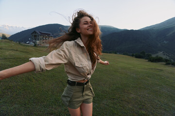 Fototapeta premium Smiling woman with long hair wearing a beige shirt and khaki shorts in a grassy field, capturing an outdoor lifestyle moment filled with happiness and nature. Bright mood and color