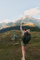 Fototapeta premium Woman hiker with backpack traverses a mountain trail, enjoying outdoors, expansive landscape, clear sky, sense of adventure and freedom in nature, travel lifestyle, photography moment