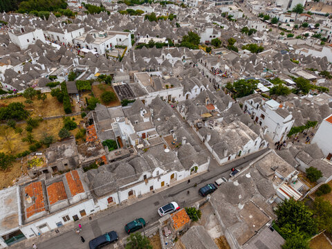 Aerial view of the historic Trulli houses with their iconic conical stone roofs and whitewashed walls lining the narrow streets under bright daylight Alberobello, Apulia, Italy.