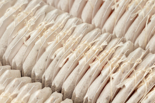 Rows of white tea bags with strings arranged in a pattern