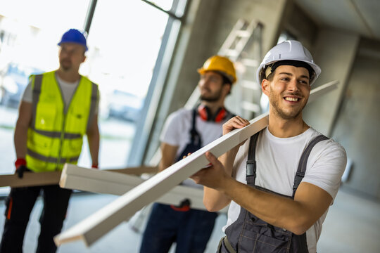 Interior renovation team carrying supplies through a building site.