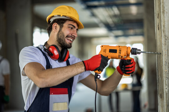 Close-up of construction worker using power drill on a concrete wall.