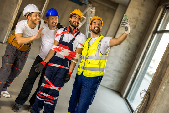 Smiling construction workers taking a selfie with a coworker wrapped in caution tape.
