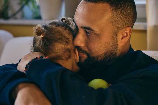 Affectionate father embracing daughter at home