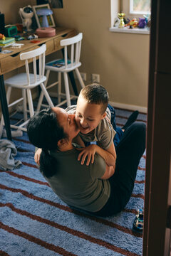 High angle view of mother kissing son while spending leisure time in bedroom at home
