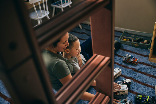 High angle view of mother spending leisure time with son playing with toy cars in bedroom at home