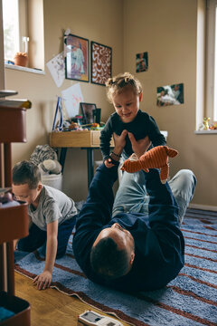 Father lying on carpet while picking up daughter and spending leisure time at home