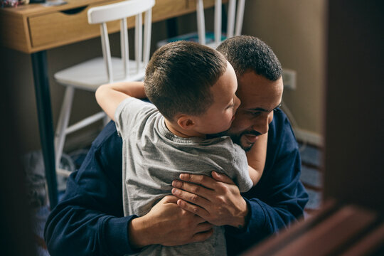 Affectionate boy embracing father at home