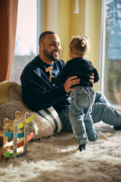 Happy father playing with daughter in living room at home