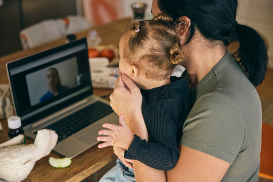 High angle view of mother explaining daughter's fever to doctor on video call through laptop while sitting in home