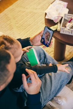 Female pediatrician on video call advising father sitting with daughter having fever at home
