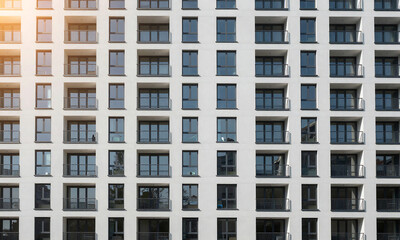 Fototapeta premium modern apartment building exterior features grid dark windows small balconies repetitive pattern creates abstract urban