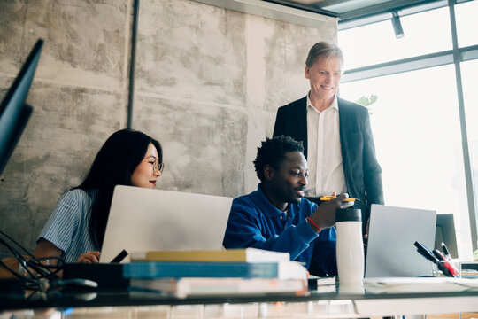 Smiling male and female employees discussing strategies with investor at office