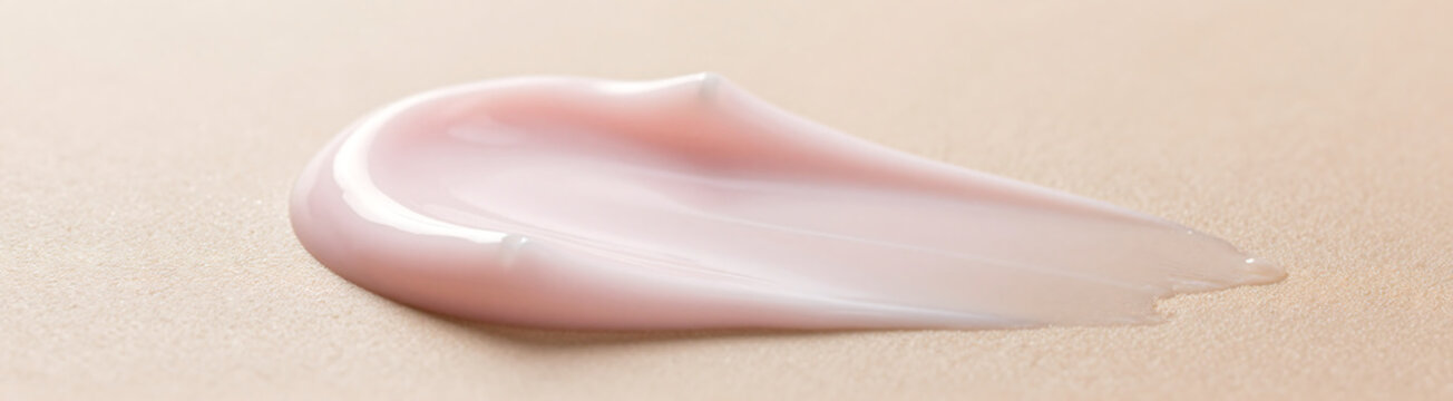 smooth pale pink skincare cream spreading soft flowing waves clean skin surface warm natural light subtle