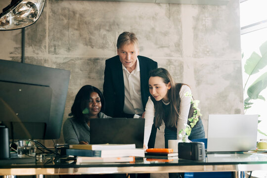 Startup team showing their project on laptop to male investor in modern office