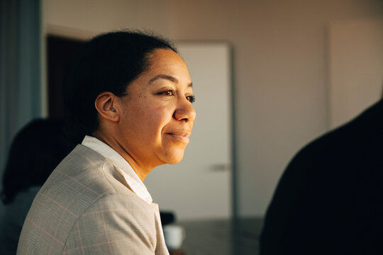 Side view of female investor sitting in team meeting at modern startup office