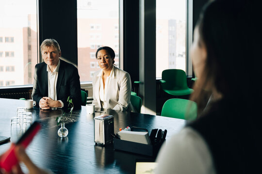 Mature male and female investors listening to presentation from colleague in meeting room