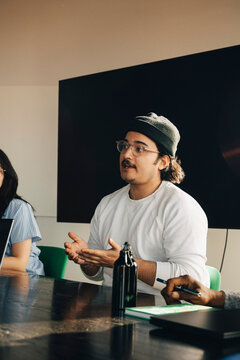 Male employee sharing business ideas during team meeting at creative workspace