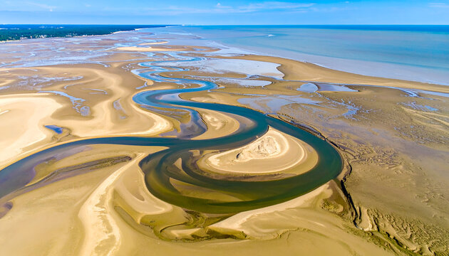 Aerial view of winding river flowing through sandy beach landscape under bright sky