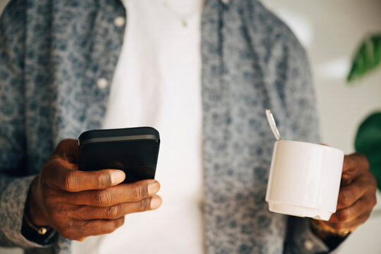Midsection of businessman scrolling smart phone during coffee break