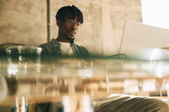 Focused businessman working on laptop while sitting at glass desk in office